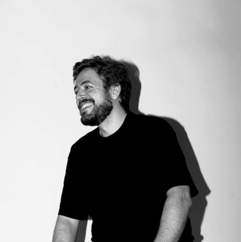 Black and white portrait of Šimon Leška smiling in a black T-shirt